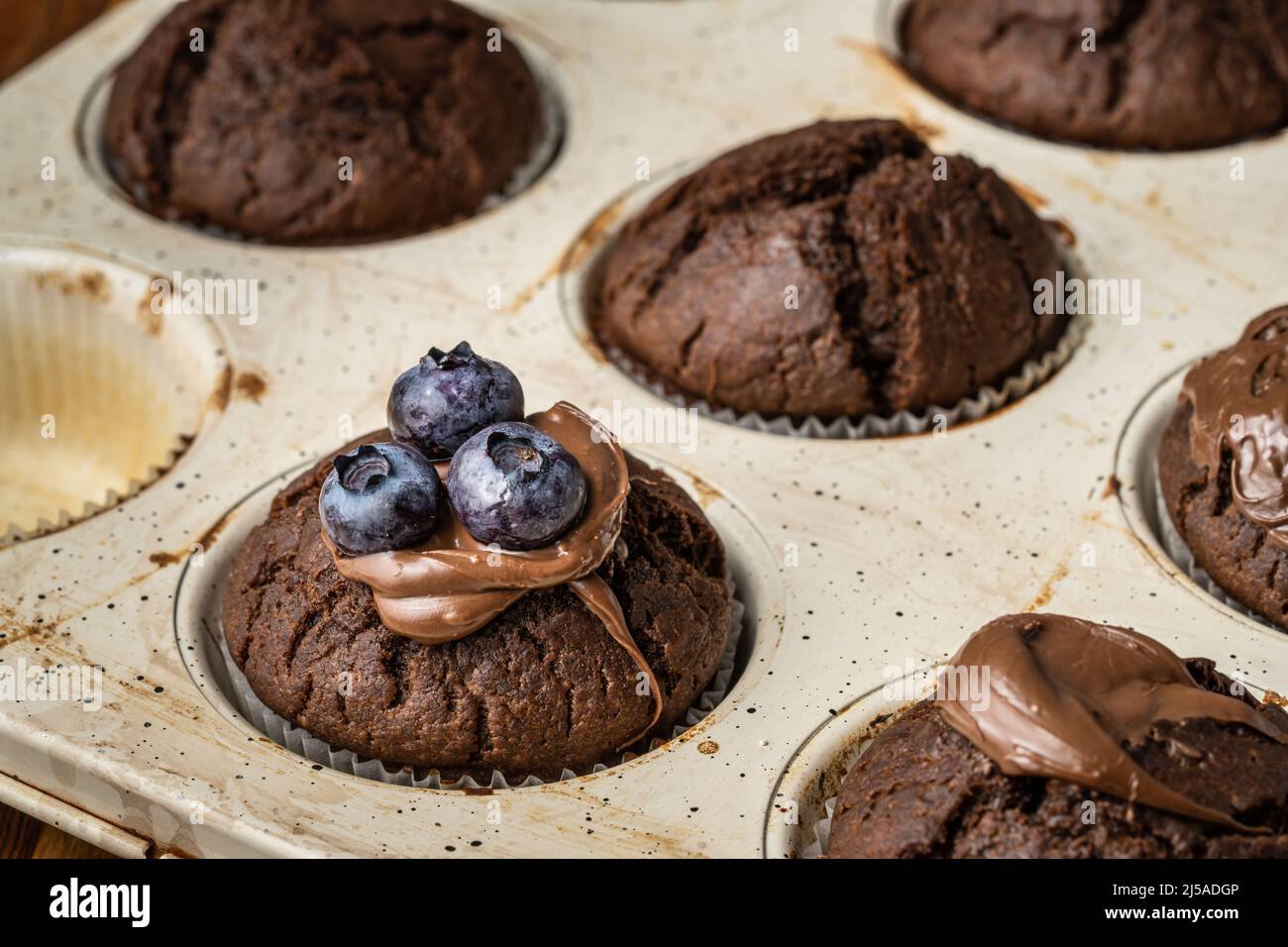 fresh baked muffins with chocolate cream and blueberries in ceramic pan Stock Photo