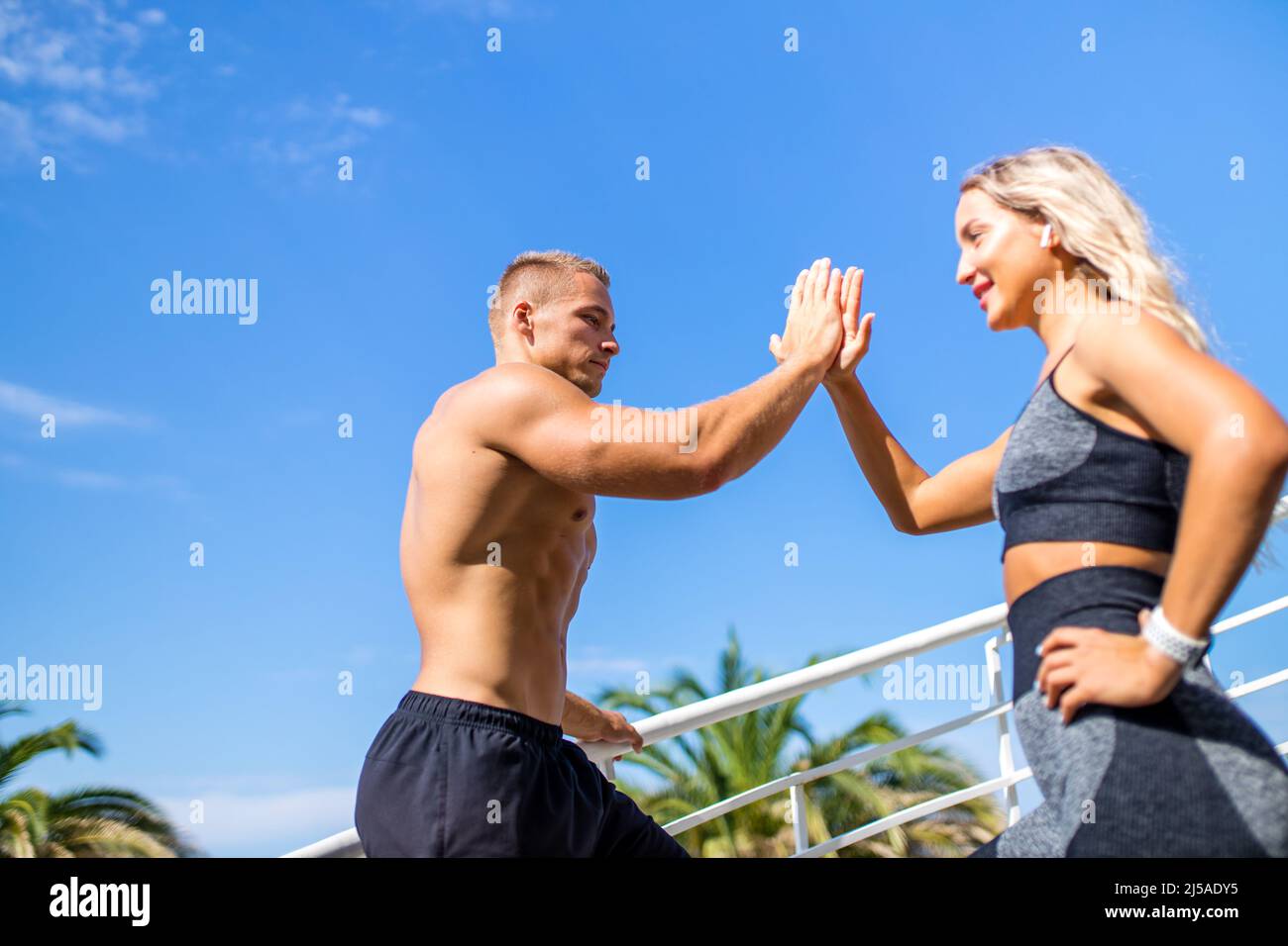 Young couple in sports outfit doing morning workout outdoors in hot summer Stock Photo
