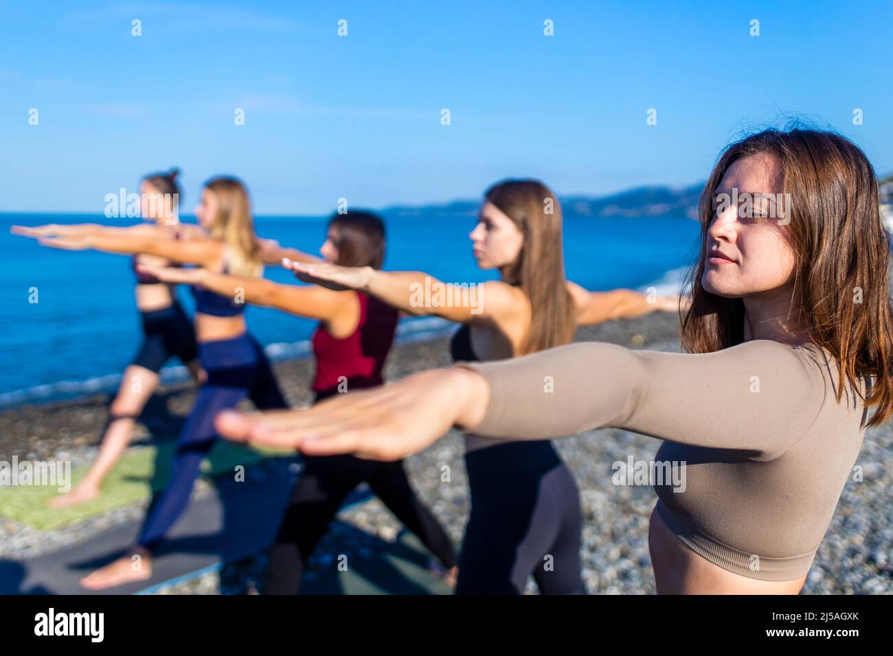 unity group of women practic yoga on rhe beach in morning Stock Photo
