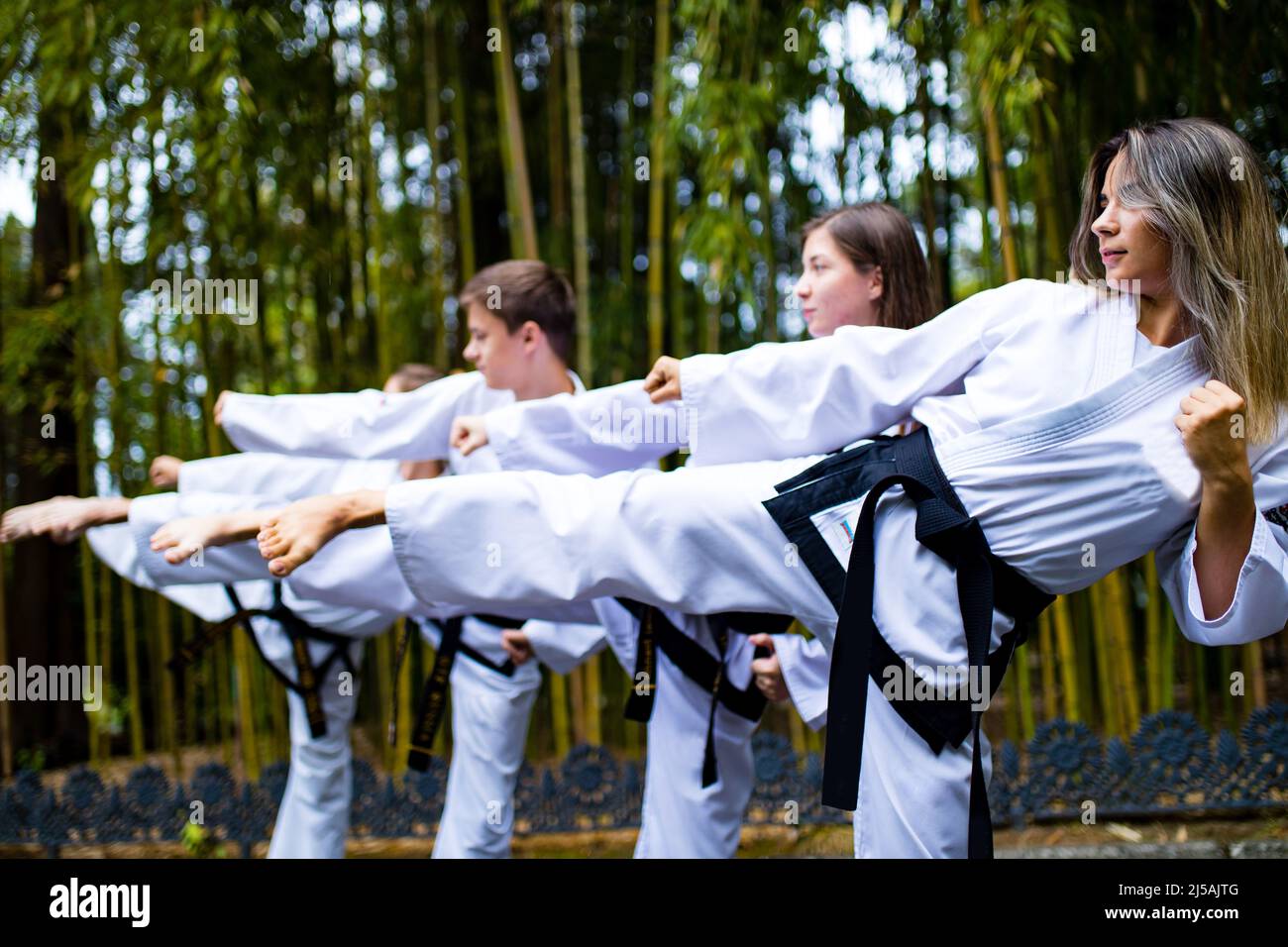 people high kicks during training of taekwondo outdoors bamboo