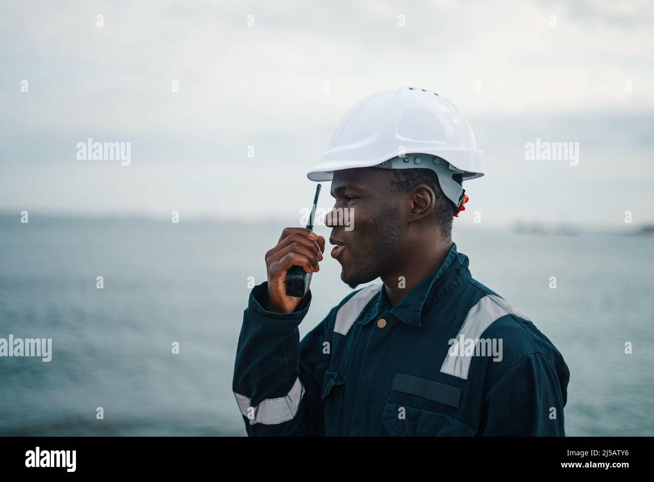 Marine Deck Officer or Chief mate on deck of vessel or ship with VHF walkie-talkie radio  Stock Photo