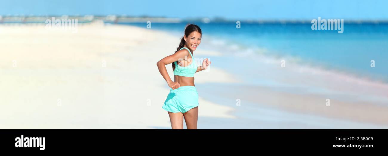 Happy running fitness girl looking back smiling on beach run jogging active healthy lifestyle. Asian woman athlete exercising cardio working out in Stock Photo