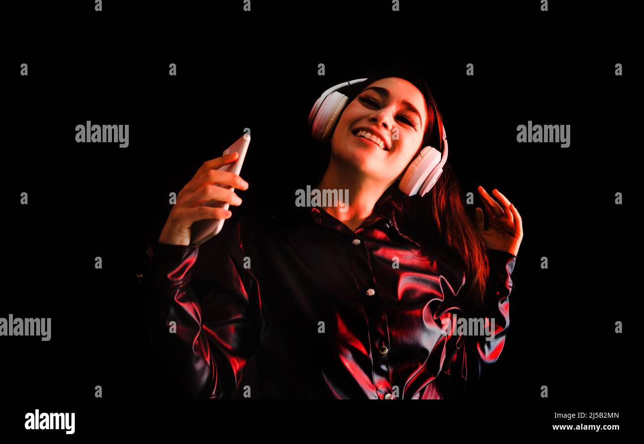 latin young woman with headphones listening to music over color neon ...