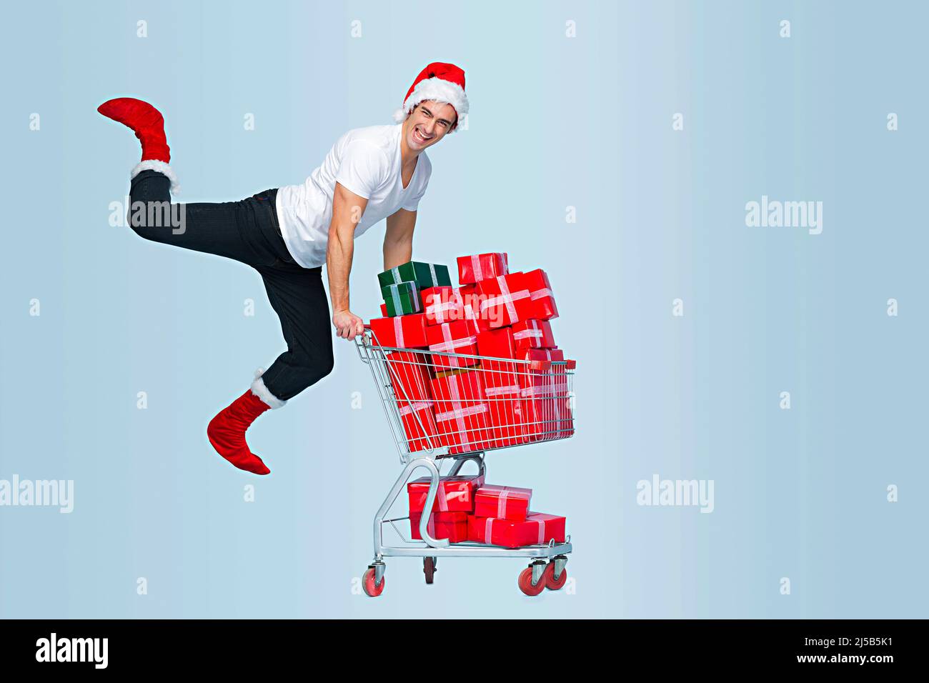 Man having many gift boxes in a shopping cart and jumping Stock Photo