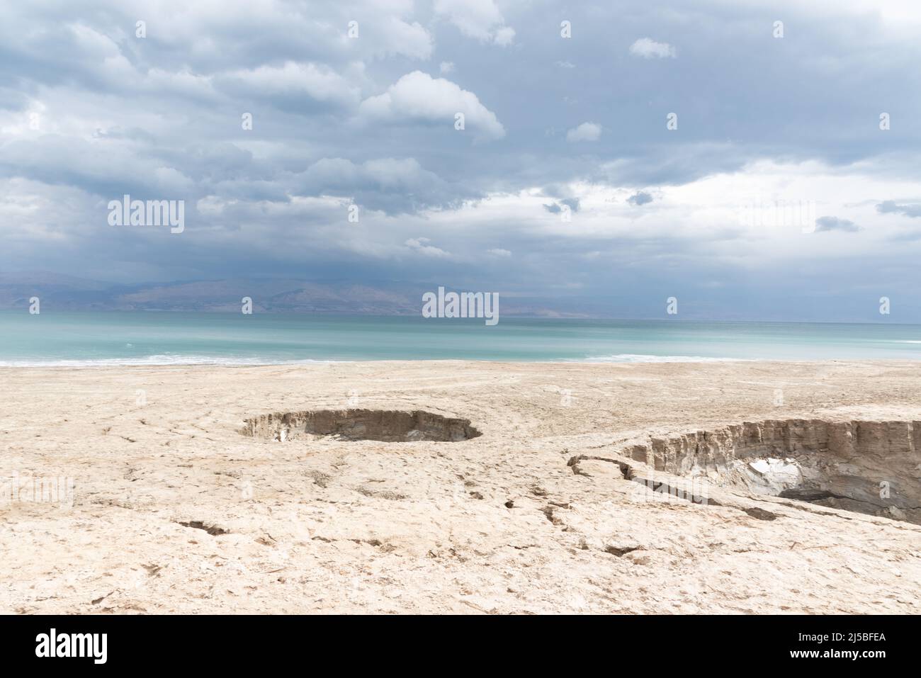 Sinkhole filled with turquoise water, near Dead Sea coastline. Hole formed when underground salt is dissolved by freshwater intrusion, due to continuing sea-level drop. . High quality photo Stock Photo