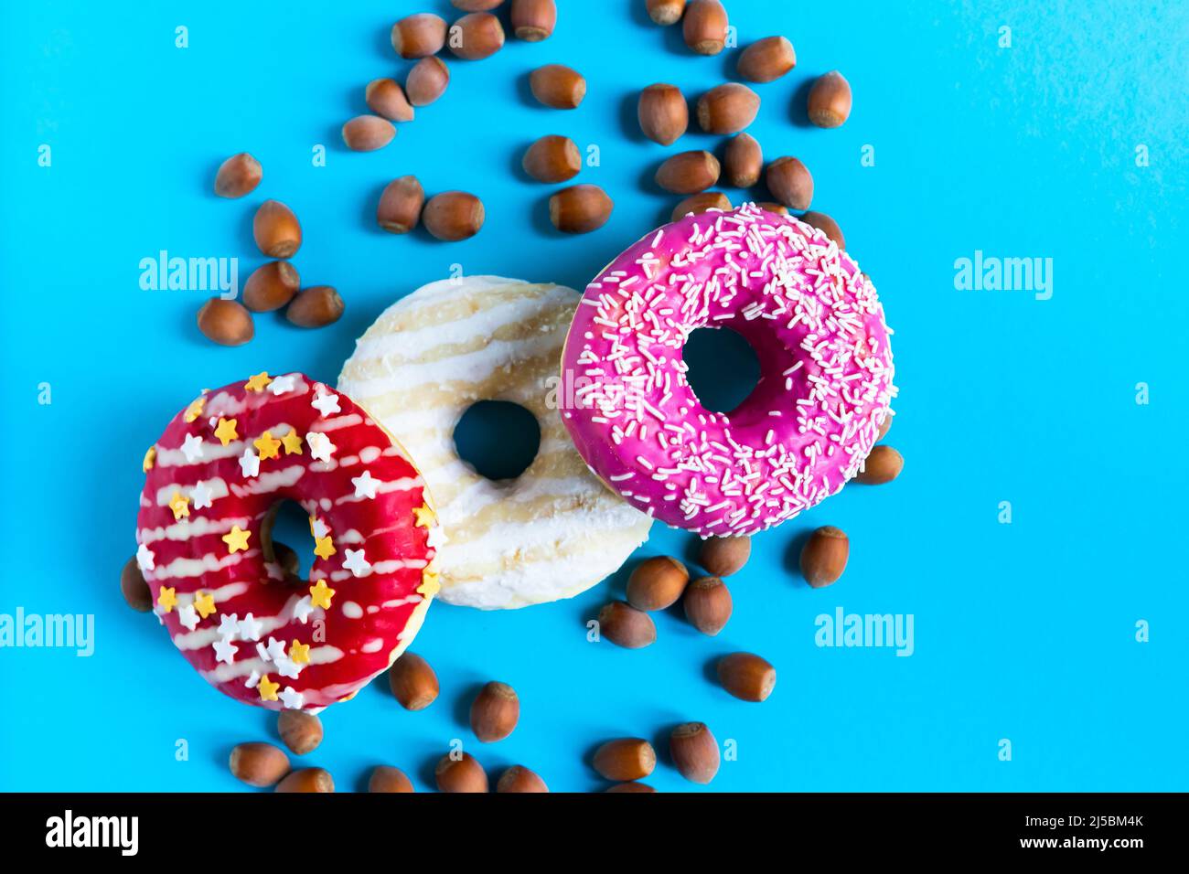 Donut with hazelnuts on a blue background, close up Stock Photo