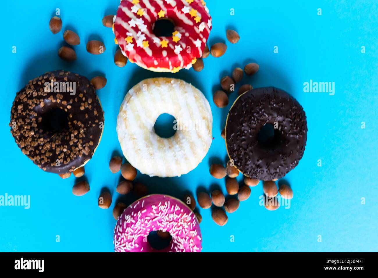 Donut with hazelnuts on a blue background, close up Stock Photo