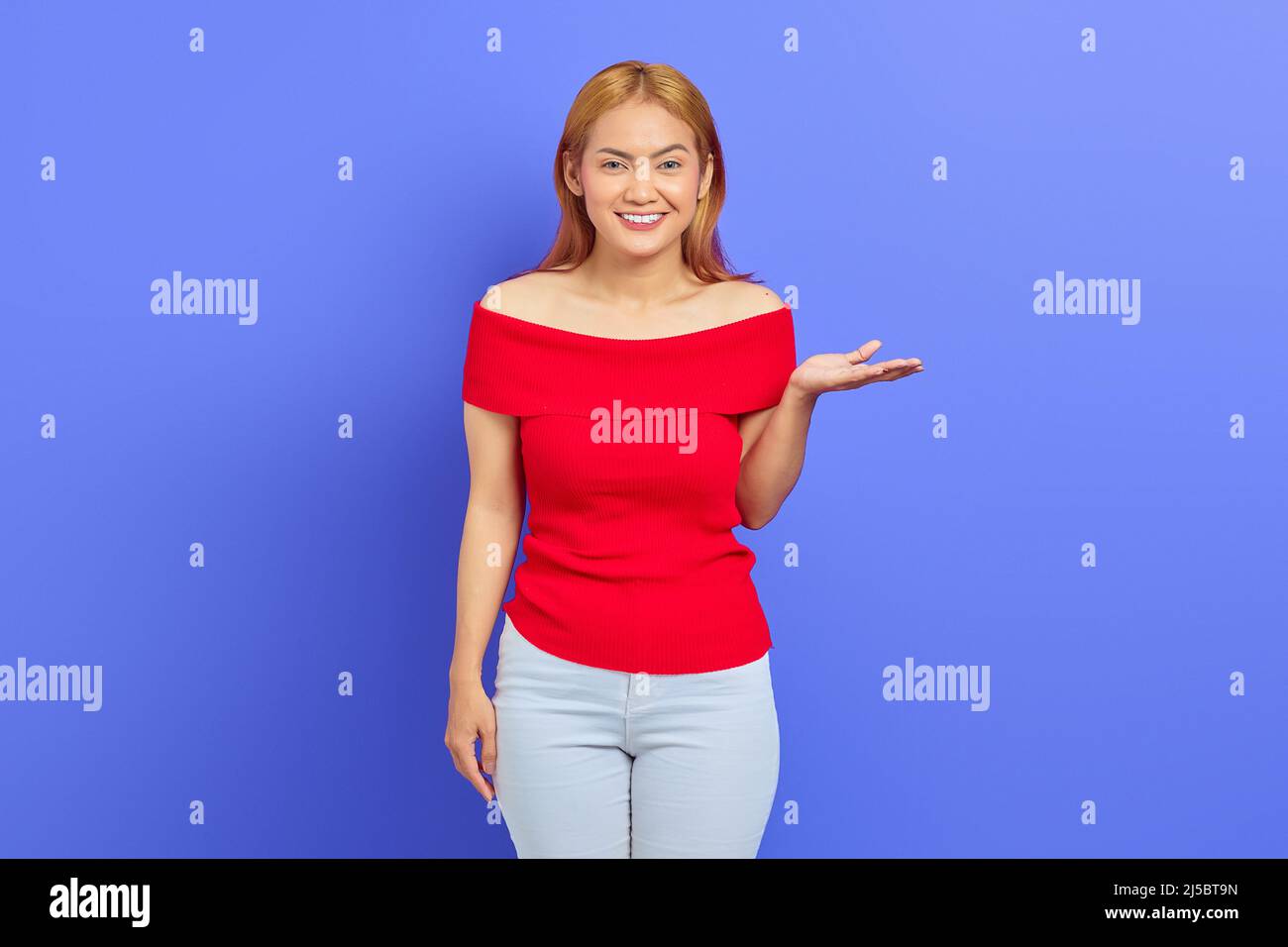 Portrait of cheerful young Asian woman in red dress, presenting copy ...