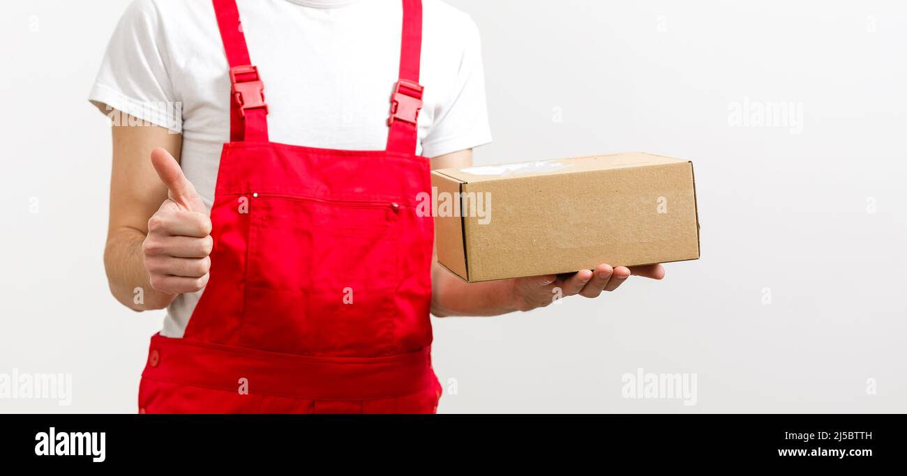 mage of a happy young delivery man in red cap standing with parcel post ...
