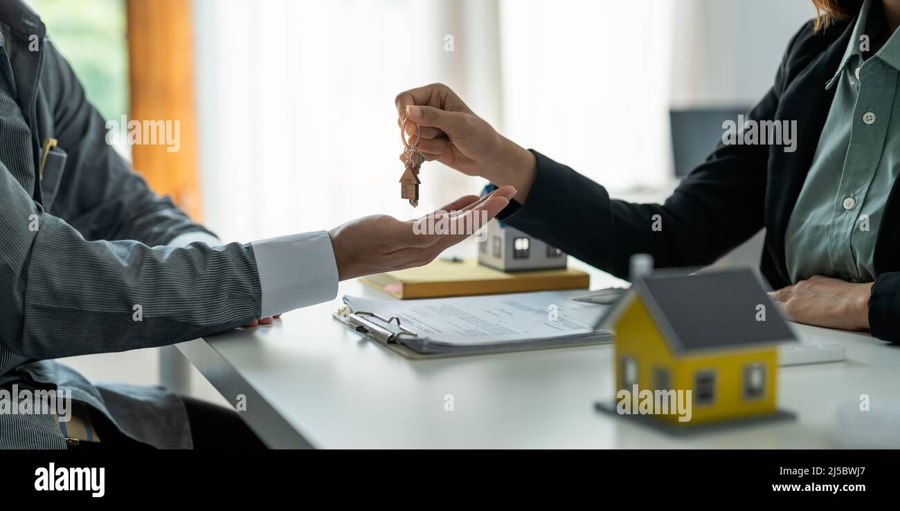 Real estate agent holding house key to his client after signing