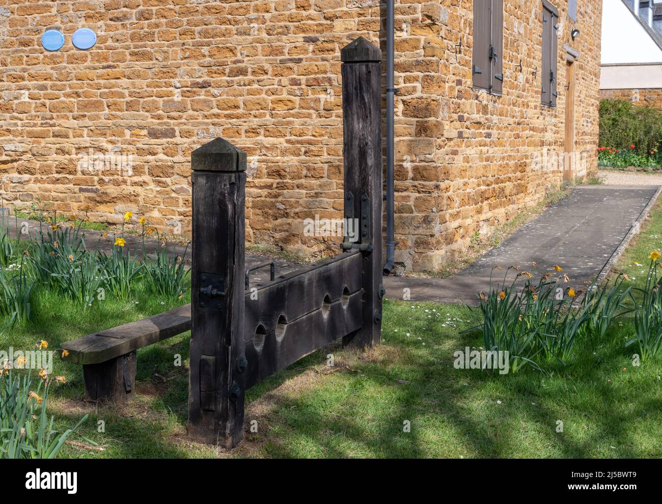 The Heritage Centre with wooden stocks in front, Brixworth village, Northamptonshire, UK; the stocks areprobably 1960's replacements of the originals Stock Photo