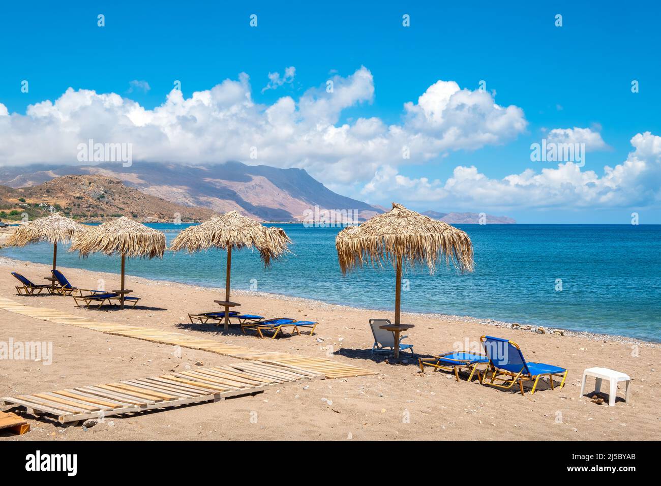 View to sun loungers and straw parasols on a beach. Kissamos, Crete, Greece Stock Photo