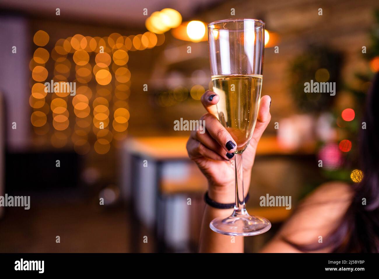 indian woman drinking alcohol at studio shot spruce Christmas tree lights garland background Stock Photo