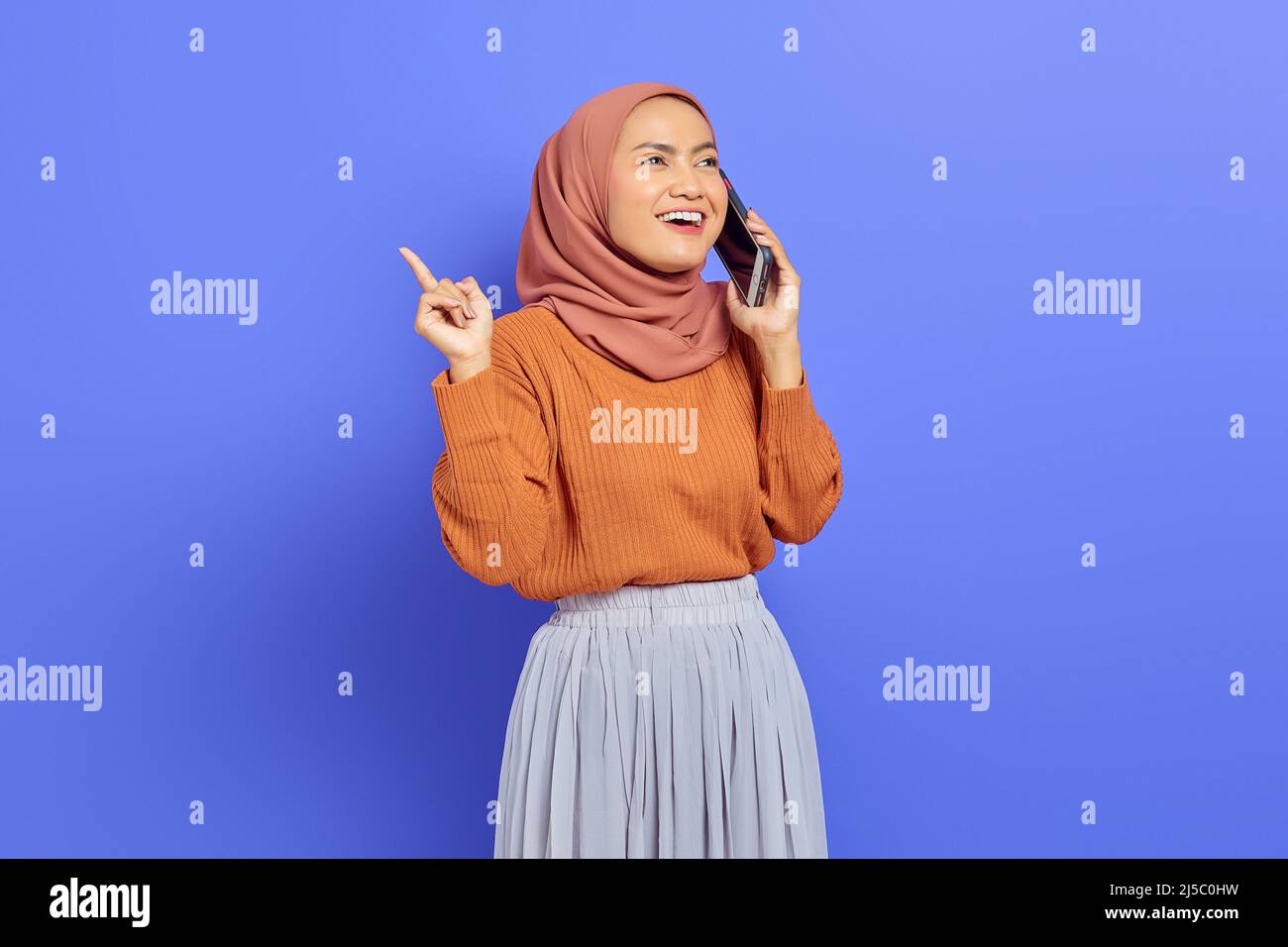 Portrait of smiling beautiful Asian woman in brown sweater and hijab ...