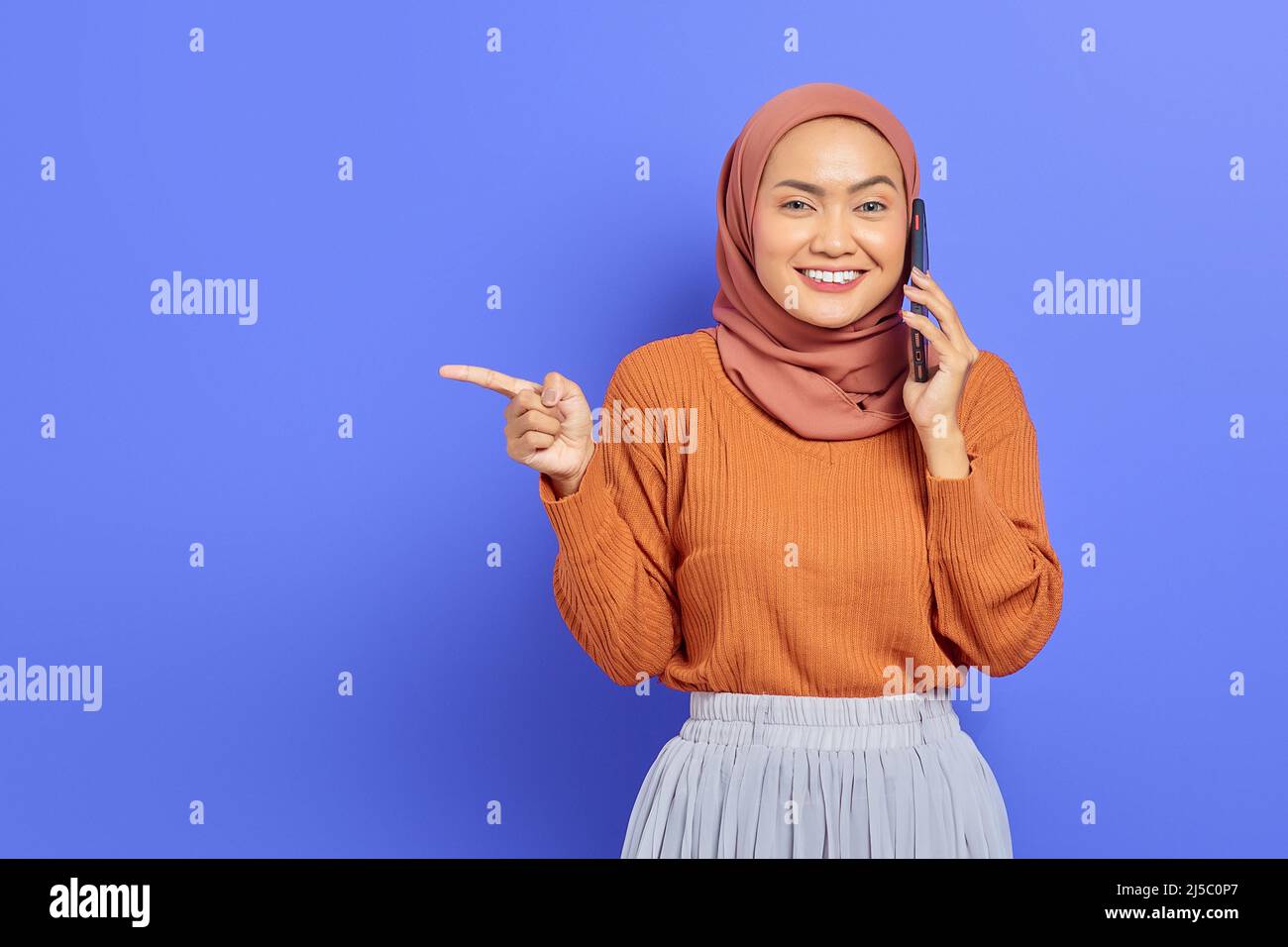 Portrait of smiling beautiful Asian woman in brown sweater and hijab ...