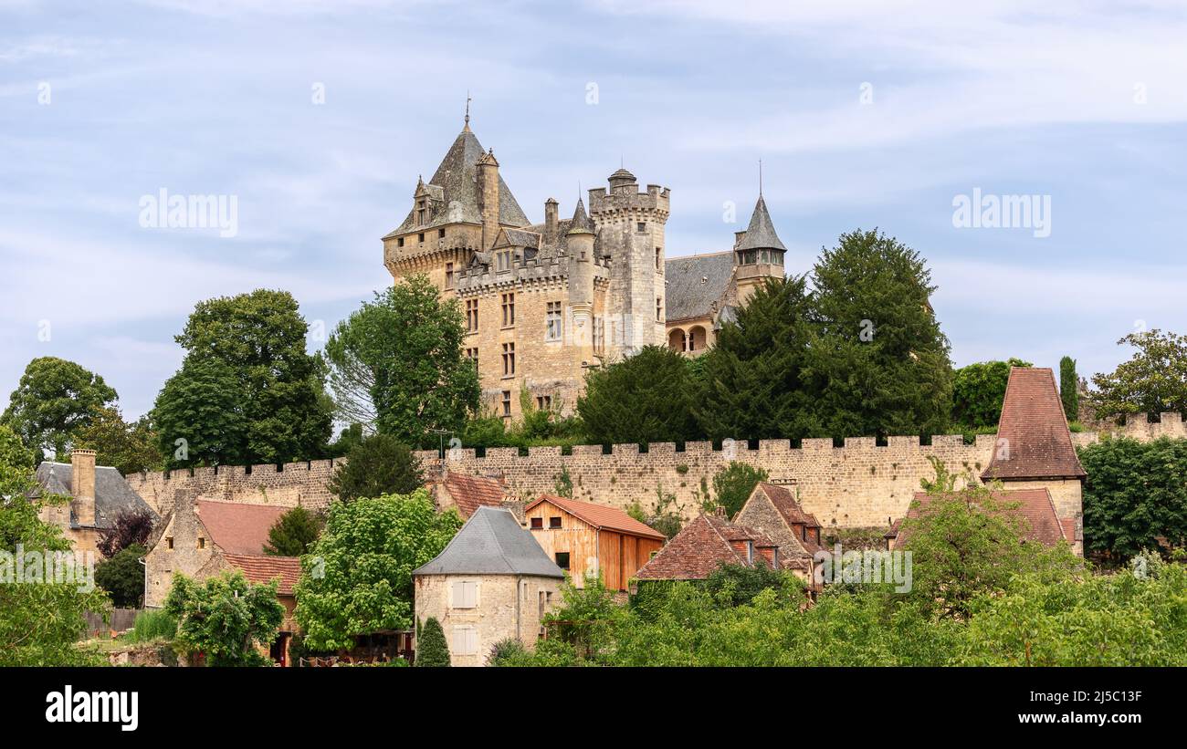 Chateau de Montfort on hill top and village huddled below substantial ramparts of castle with attractive houses in Dordogne region, France Stock Photo