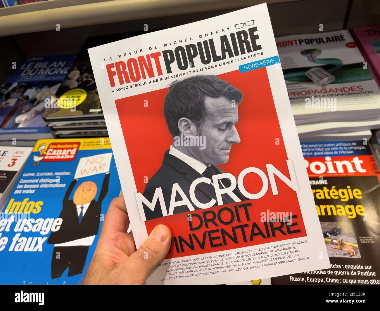 Paris, France - Apr 11, 2022: POV male hand buy Front populaire magazine newspaper press headlines with French President Emmanuel Macron - presidential election of 2022 Stock Photo
