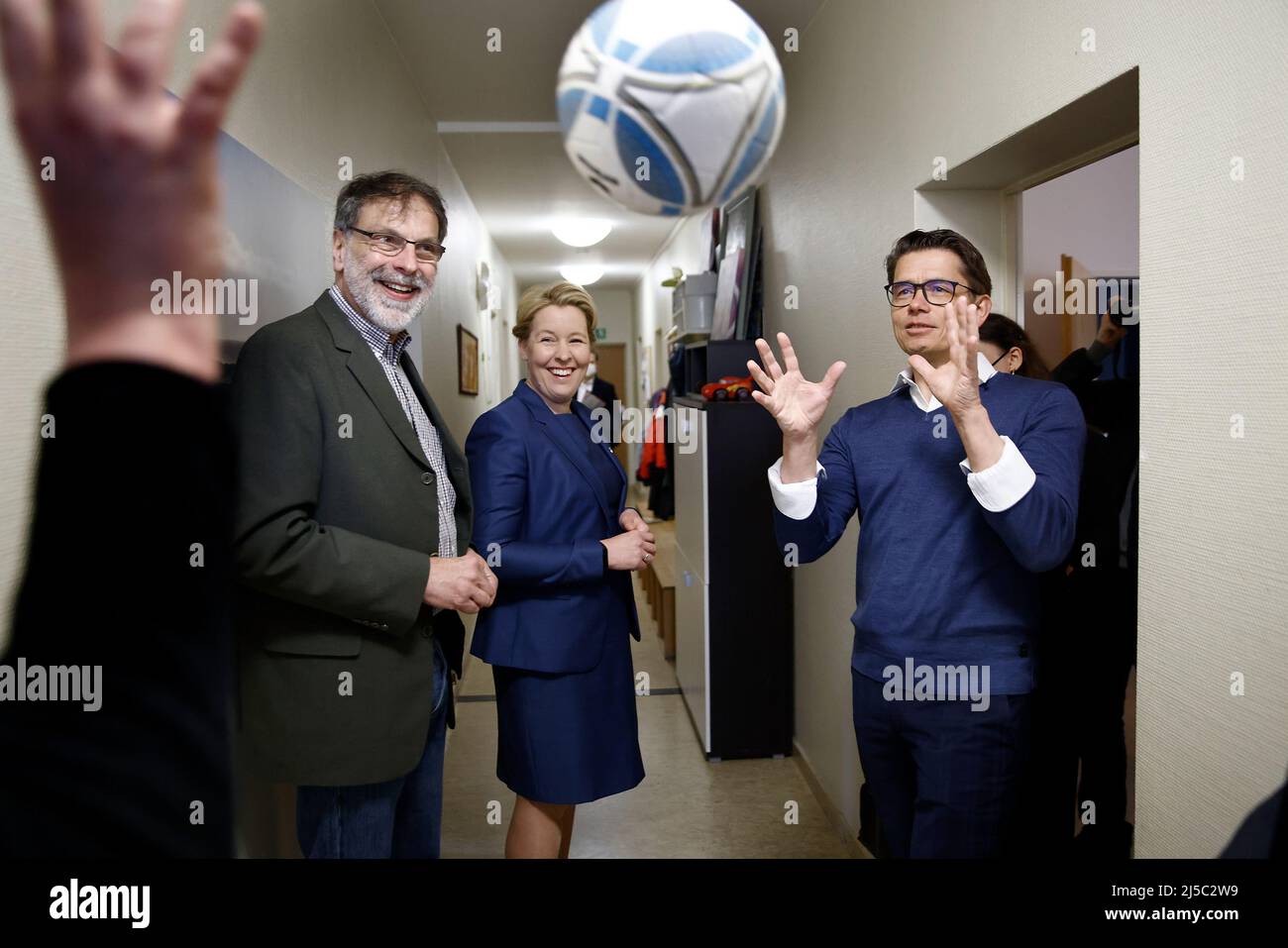 Berlin, Germany. 22nd Apr, 2022. An employee throws a ball while Franziska Giffey (SPD), governing mayor of Berlin, talks to Helmut Wegner (l), managing director and director of the Elisabethstift children's home, and Marcus Dröge (r), managing director of TIB Molbiol and presenter of a donation check from his company to the Elisabethstift children's home to support the care of Ukrainian refugee children. Giffey visited the children's home on Friday to learn about the work with Ukrainian children on site. Credit: Carsten Koall/dpa/Alamy Live News Stock Photo
