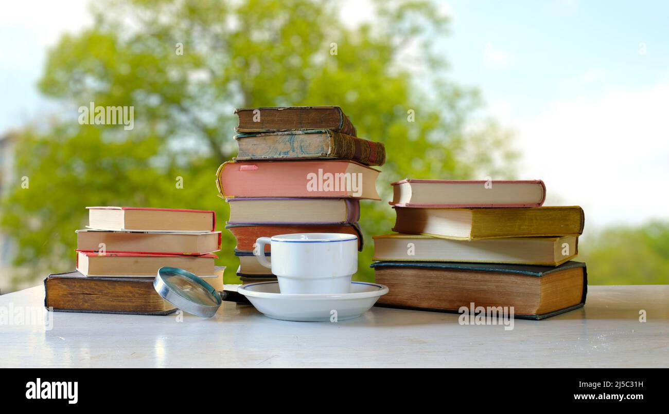 home office,education,business,concept with  heap of books and cup of coffee,blurred nature background,home office saves co2 Stock Photo