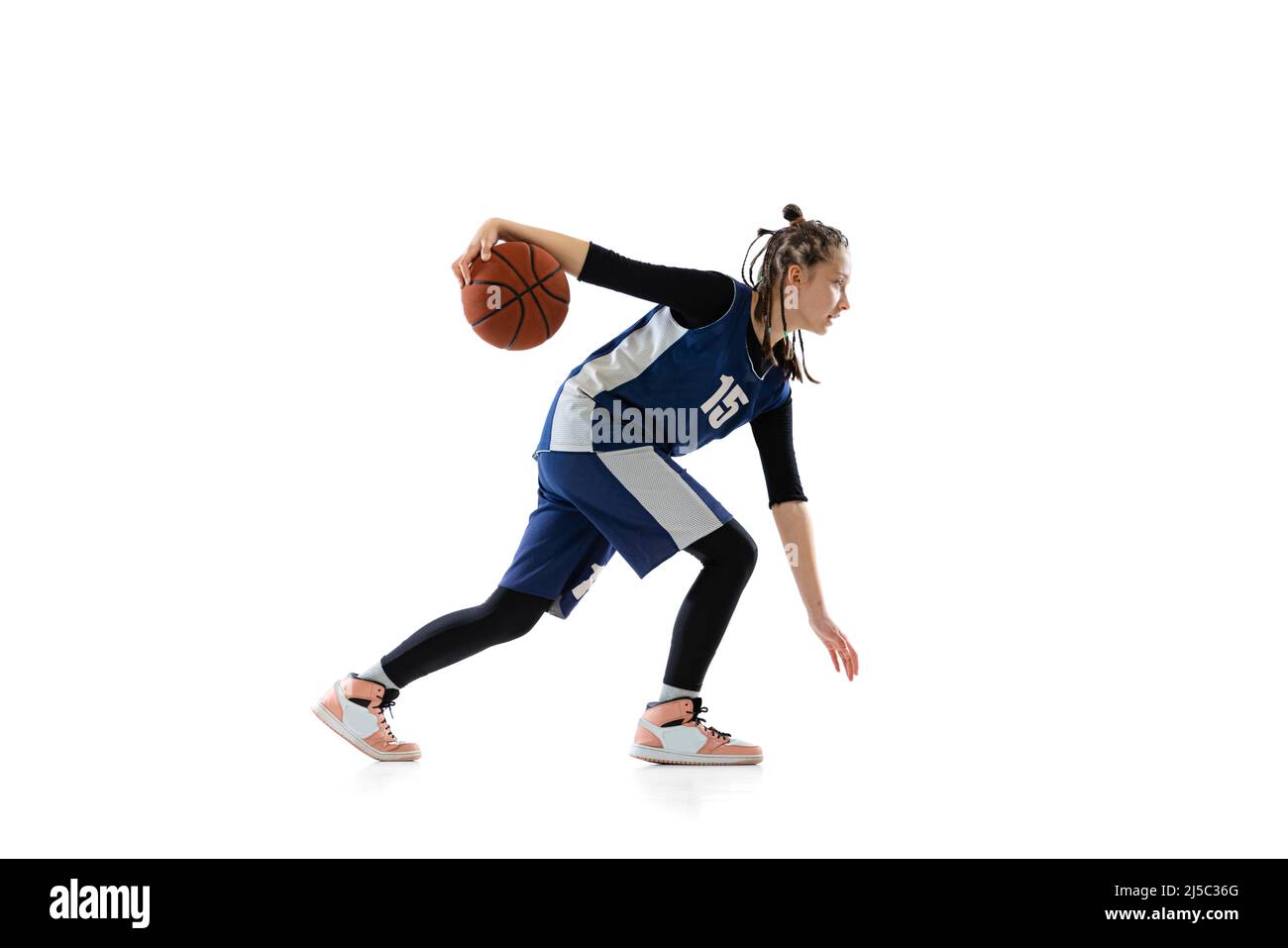 Fulllength side view studio shot of young girl, basketball player in