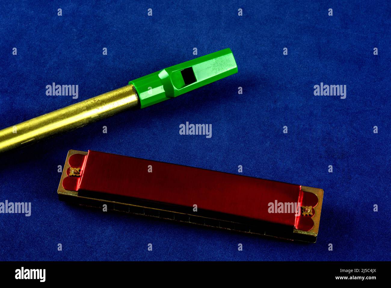 Old harmonica and tin whistle on a blue background Stock Photo