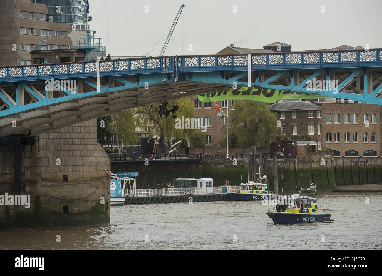 Extinction Rebellion protesters suspend themselves by ropes beneath Tower Bridge. Hanging 'END FOSSIL FUELS NOW' banner. Stock Photo