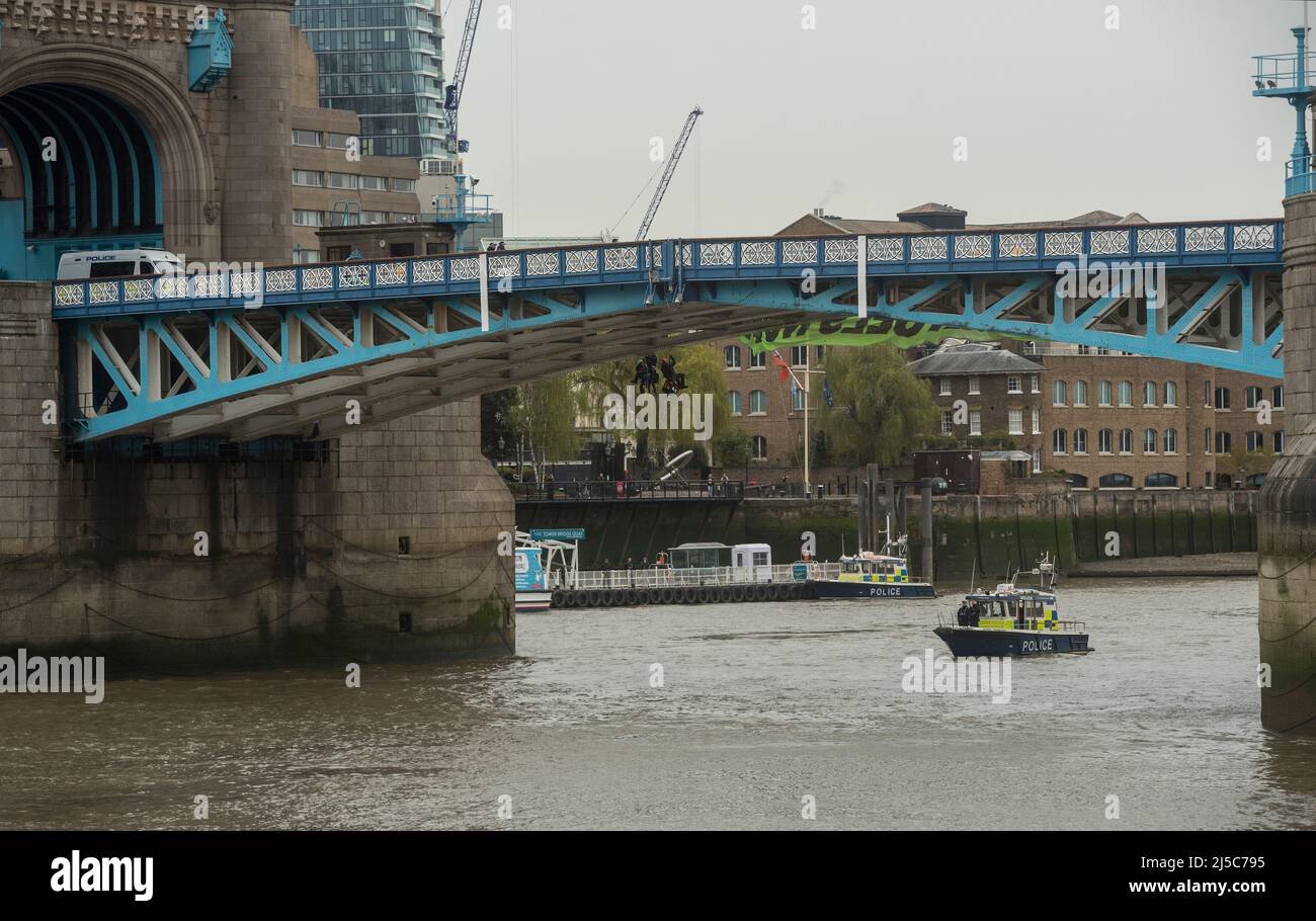 Extinction Rebellion protesters suspend themselves by ropes beneath Tower Bridge. Hanging 'END FOSSIL FUELS NOW' banner. Stock Photo