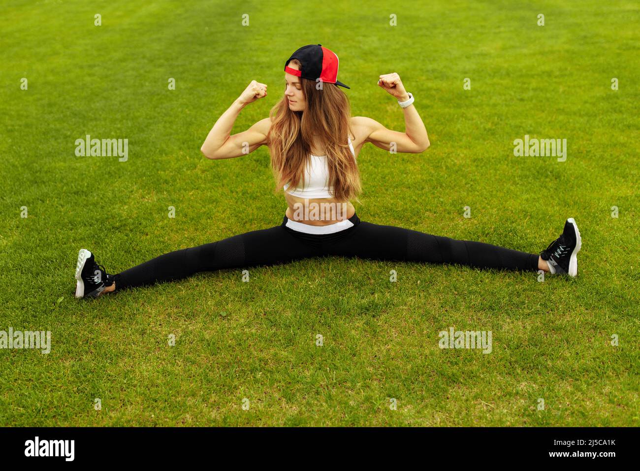 Sporty woman posing with muscles at the stadium, doing stretching, practice flexibility, recommended healthy lifestyle, daily workout concept  Stock Photo