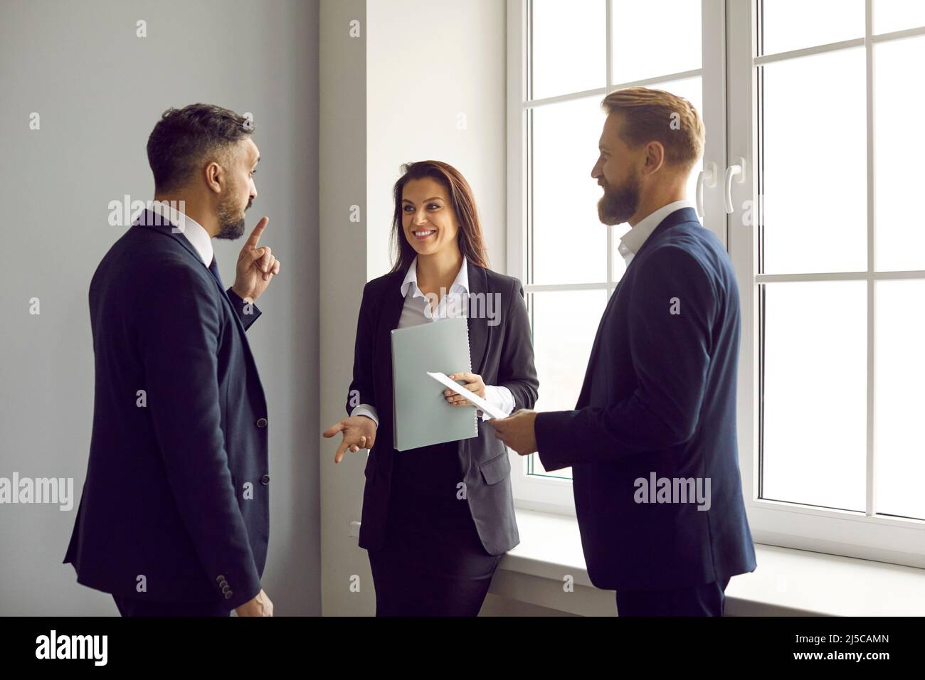 Group of happy business colleagues standing in the office and having a conversation Stock Photo