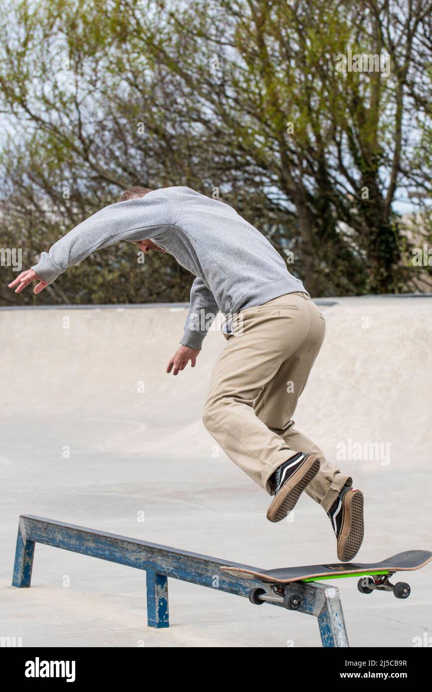 A mature male skateboarder failing to perform a boardslide railslide trick at Newquay Concrete Waves Skatepark in Newquay in Cornwall in the UK. Stock Photo