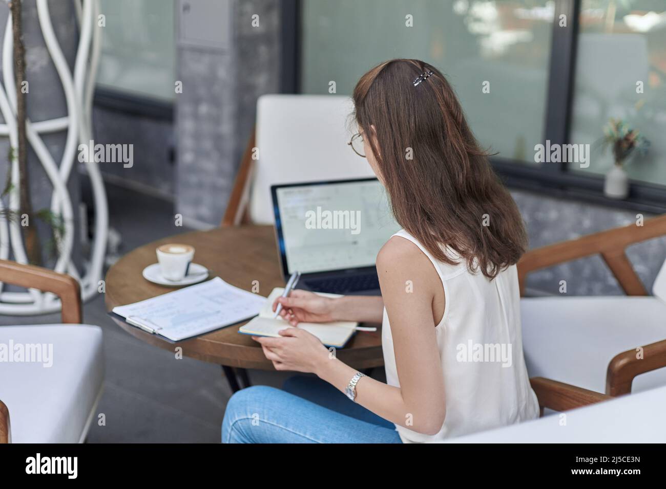 visitor to an Internet cafe making notes in a notebook. Stock Photo