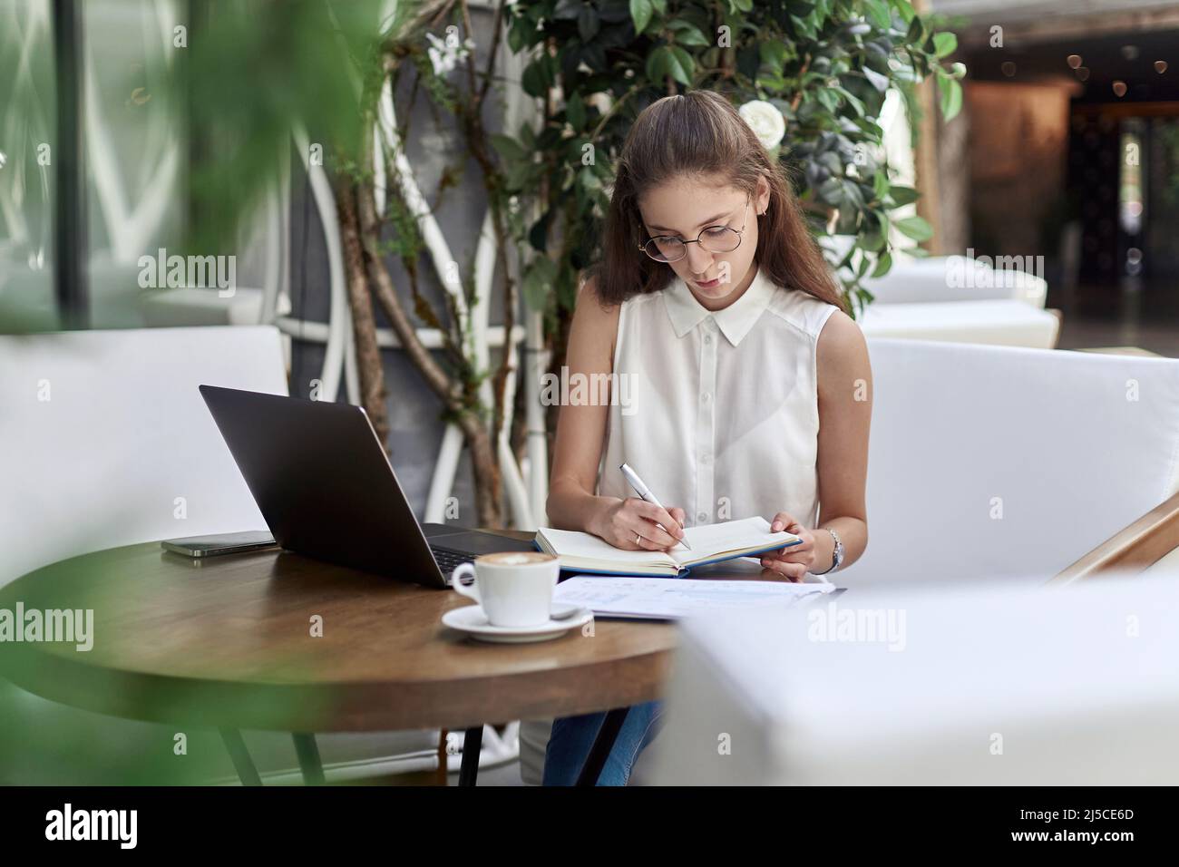 visitor to an Internet cafe making notes in a notebook. Stock Photo