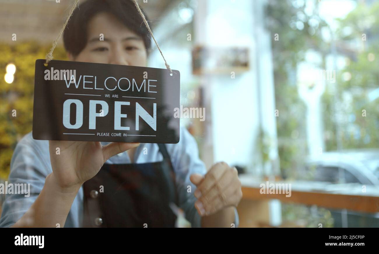 Business owner asian woman turning Sorry closed sign on fronton glass door store. Stock Photo