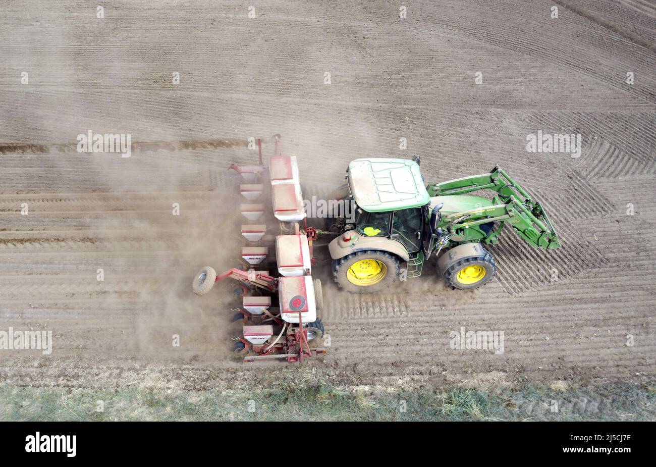 Due to the persistent drought, a tractor is dragging a large plume of dust behind it as it sows corn. [automated translation] Stock Photo