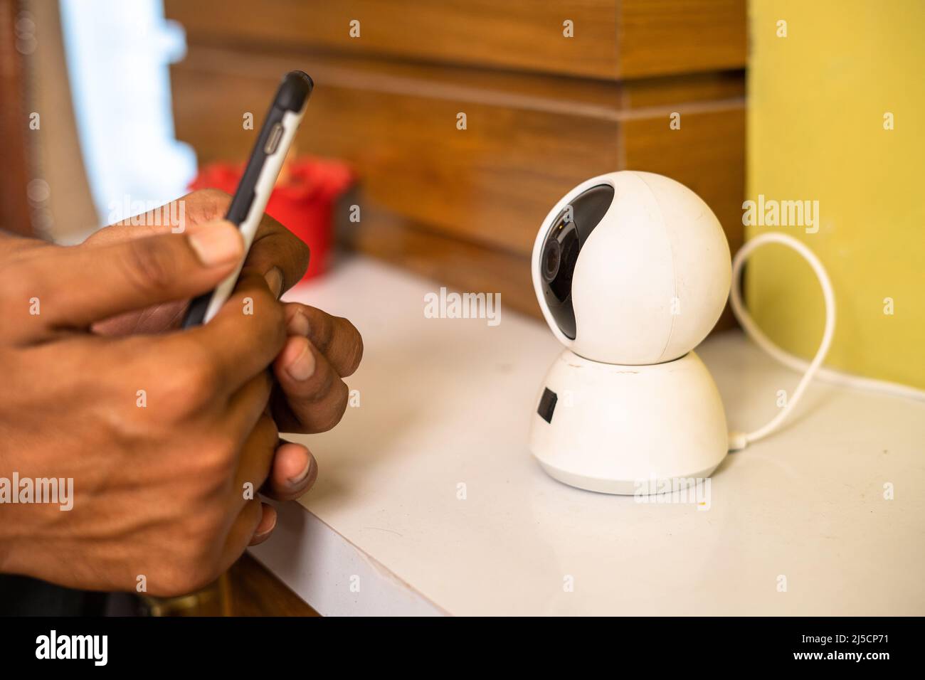 Close up shot of hands scanning smart cctv home surveillance camera on mobile phone at home - concepts of smar home, safety and security. Stock Photo