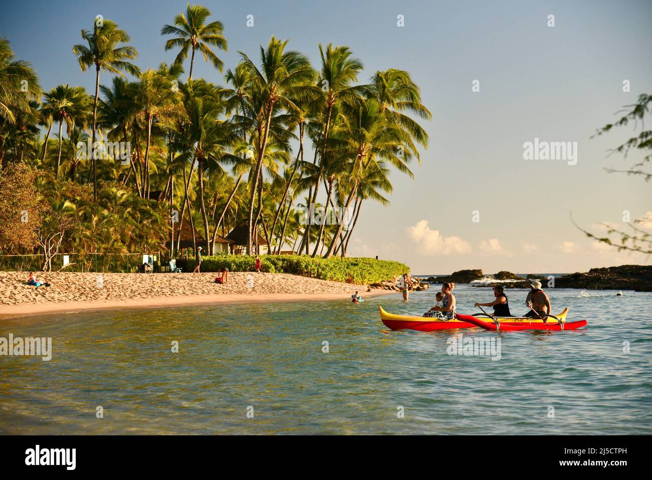 Guests paddling to going on Hawaiian outrigger canoe sunset ride as a part of the Paradise Cove Luau experience on island of Oahu, Hawaii, USA Stock Photo