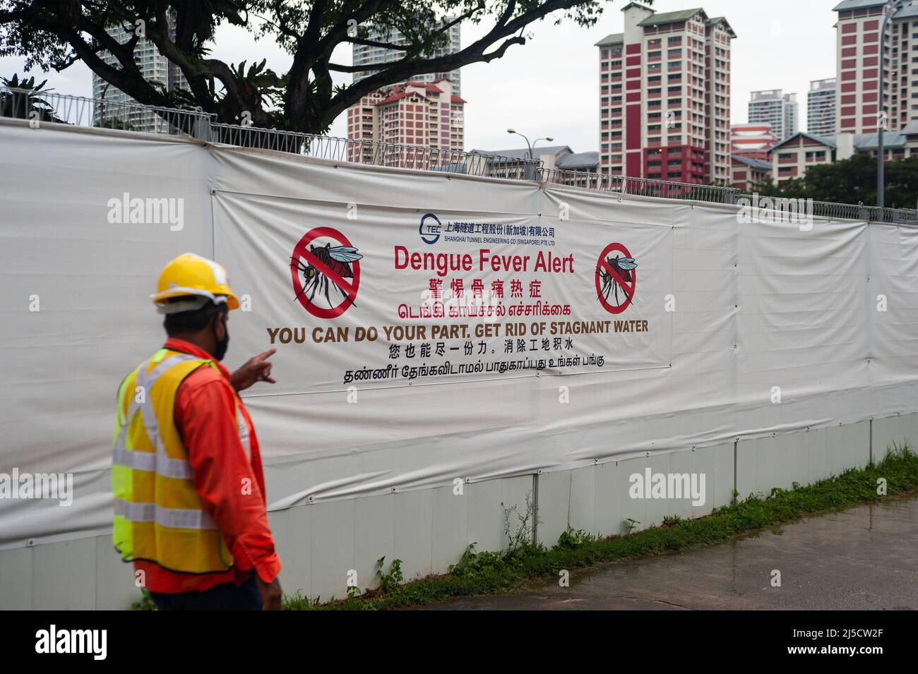 Dec. 14, 2020, Singapore, Republic of Singapore, Asia - A worker walks past a construction site in a residential neighborhood where a large banner on the construction fence warns of the risk of spreading and contracting dengue fever from mosquitoes, as they use standing water like that found on construction sites as possible breeding grounds. [automated translation] Stock Photo