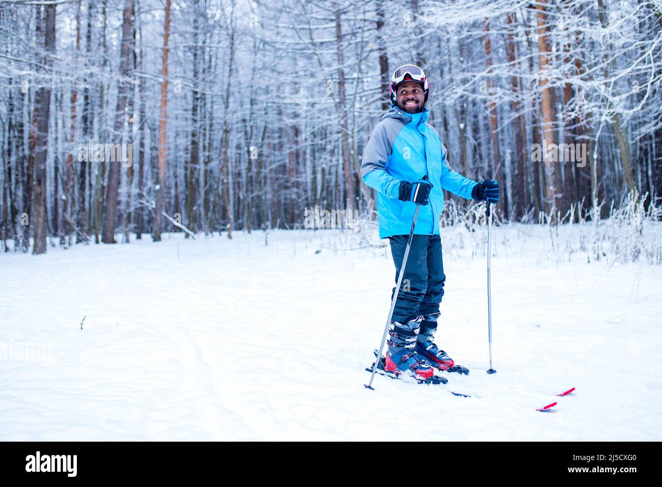 afro american man in blue jacket run ski outdoors in freeze forest ...