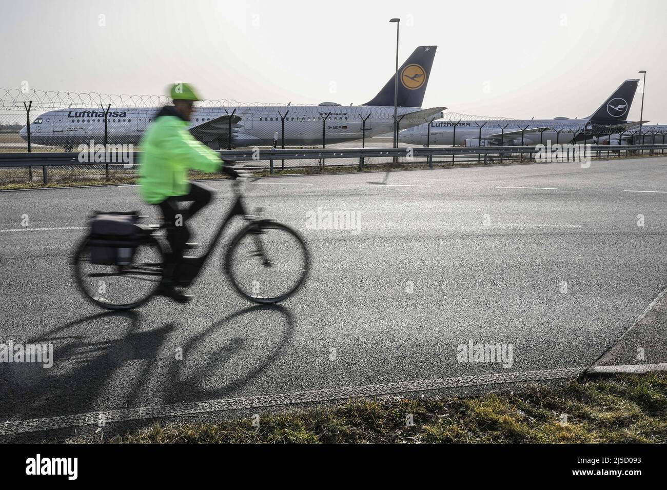 Schoenefeld, DEU, Feb. 23, 2021 - A cyclist rides past decommissioned Lufthansa aircraft at BER Airport.Lufthansa had to decommission a large number of its 760 aircraft due to the Corona crisis. [automated translation] Stock Photo