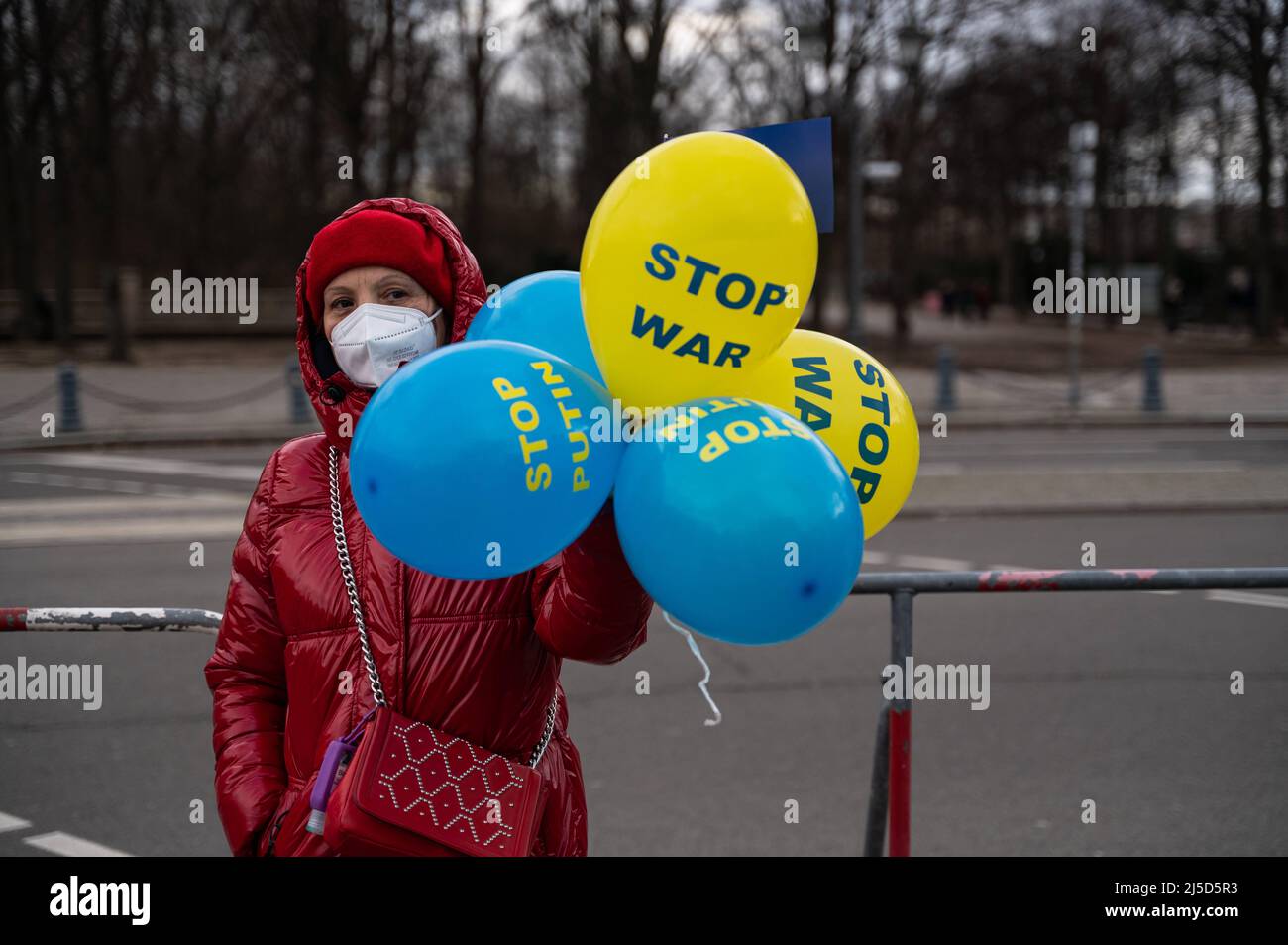 'Feb. 19, 2022, Berlin, Germany, Europe - A demonstrator wearing a Corona mouth guard holds balloons and protests against an imminent invasion by Russia and a possible war in Ukraine as part of a demonstration by Ukrainians and supporters living in Berlin and Germany under the slogan ''Solidarity with Ukraine - Hands off Ukraine - Stop Putin Now'' at the Platz des 18 Maerz in front of the Brandenburg Gate in Berlin-Mitte. The demonstrators demand the immediate withdrawal of Russian troops from the Ukrainian border, compliance with the Minsk ceasefire agreement and a political solution to the Stock Photo