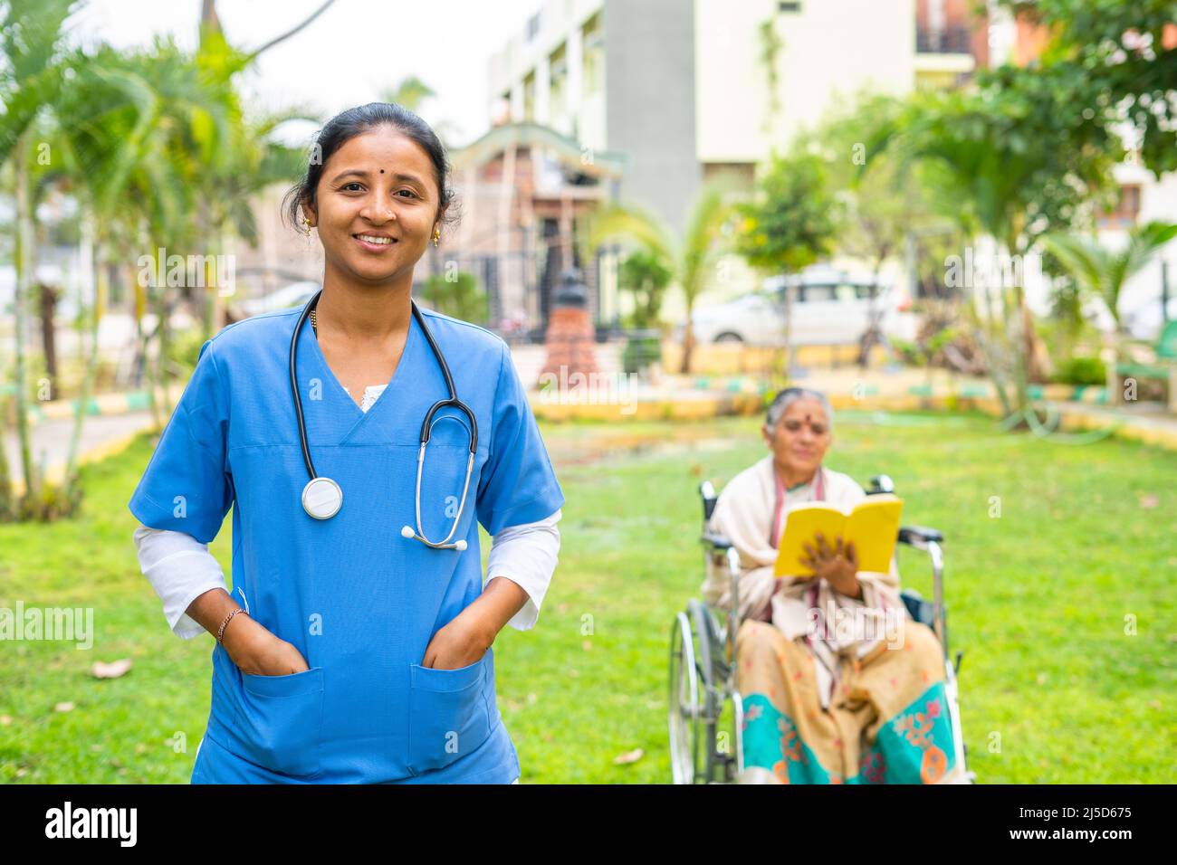 Happy Smiling Doctor Confidently Standing In Front Of Senior Patient On Wheelchair By Looking At 