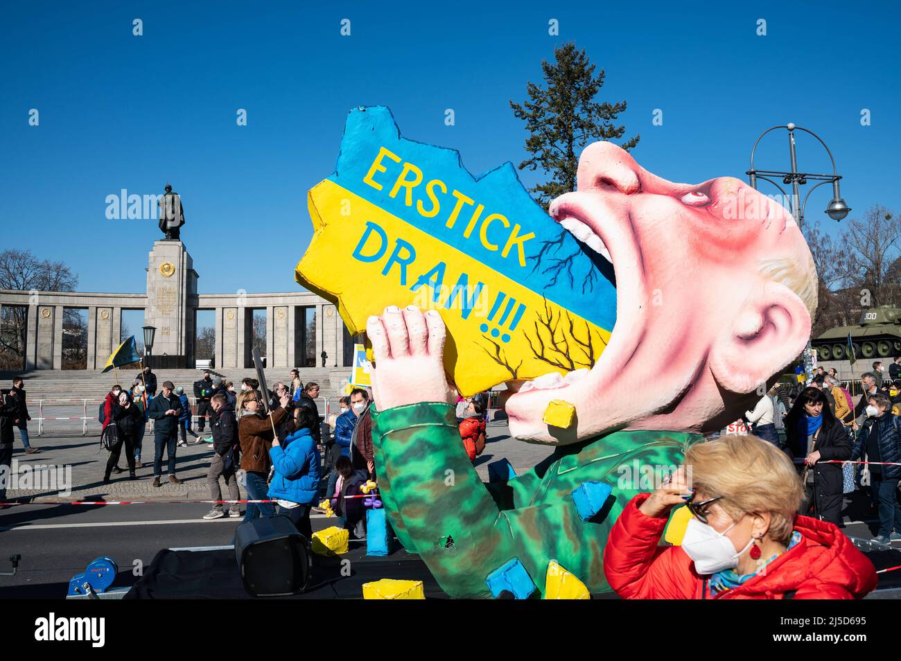 '13.03.2022, Berlin, Germany, Europe - A carnival float by sculptor and float builder Jacques Tilly passes the Soviet Memorial in the Tiergarten and shows a Vladimir Putin made of papier-mâché with the inscription ''Erstick Dran!'' trying to devour Ukraine. In Berlin, tens of thousands of people again demonstrate for peace in Europe and against Russia's war of aggression in Ukraine. The large demonstration will lead from Alexanderplatz via Potsdamer Platz to the Victory Column and will take place under the motto ''Stop the war! Peace and solidarity for the people of Ukraine''. [automated Stock Photo