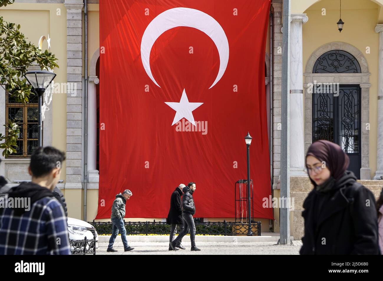 Izmir, Turkey, 19.03.2022 - Passers-by walk along a large Turkish flag in Izmir. The Turkish economy grew strongly in 2021 at eleven percent. However, the economy faces a difficult year in 2022 due to high inflation and the Ukraine war. [automated translation] Stock Photo