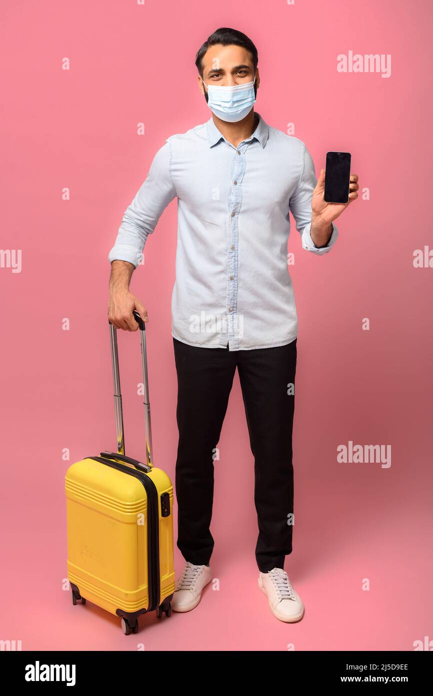 Full length Indian man in medical mask standing over pink background ...