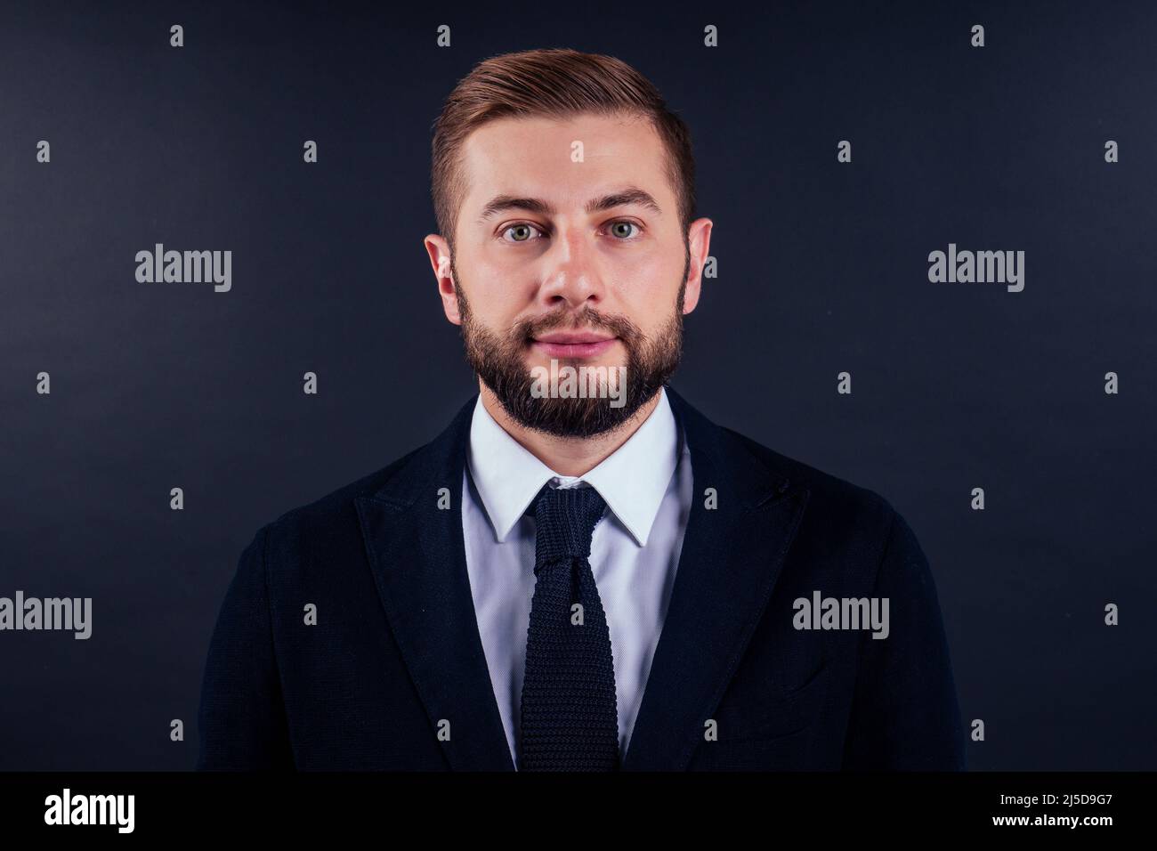 Portrait of handsome young businessman holding credit card over black background Stock Photo