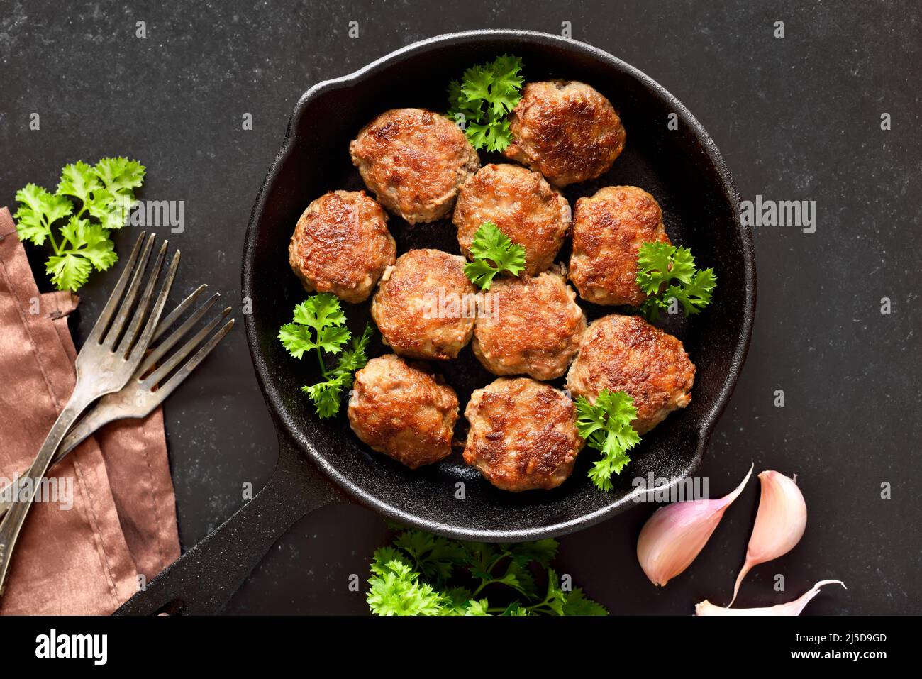 Homemade cutlets from minced meat in frying pan over black background. Top view, flat lay Stock Photo