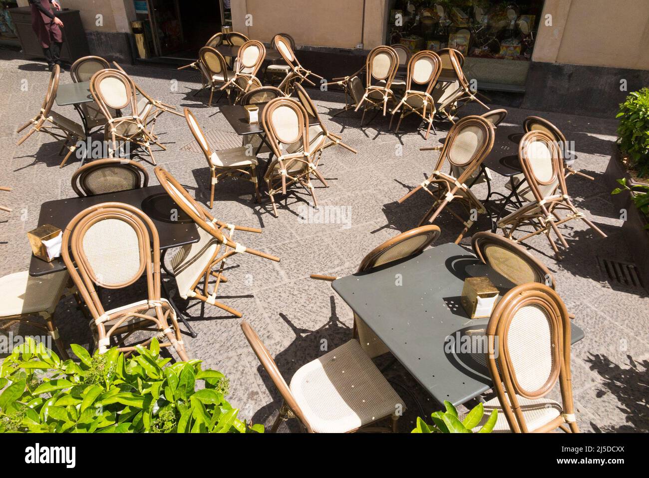 Pavement tables outside a cafe restaurant leant forwards against 
