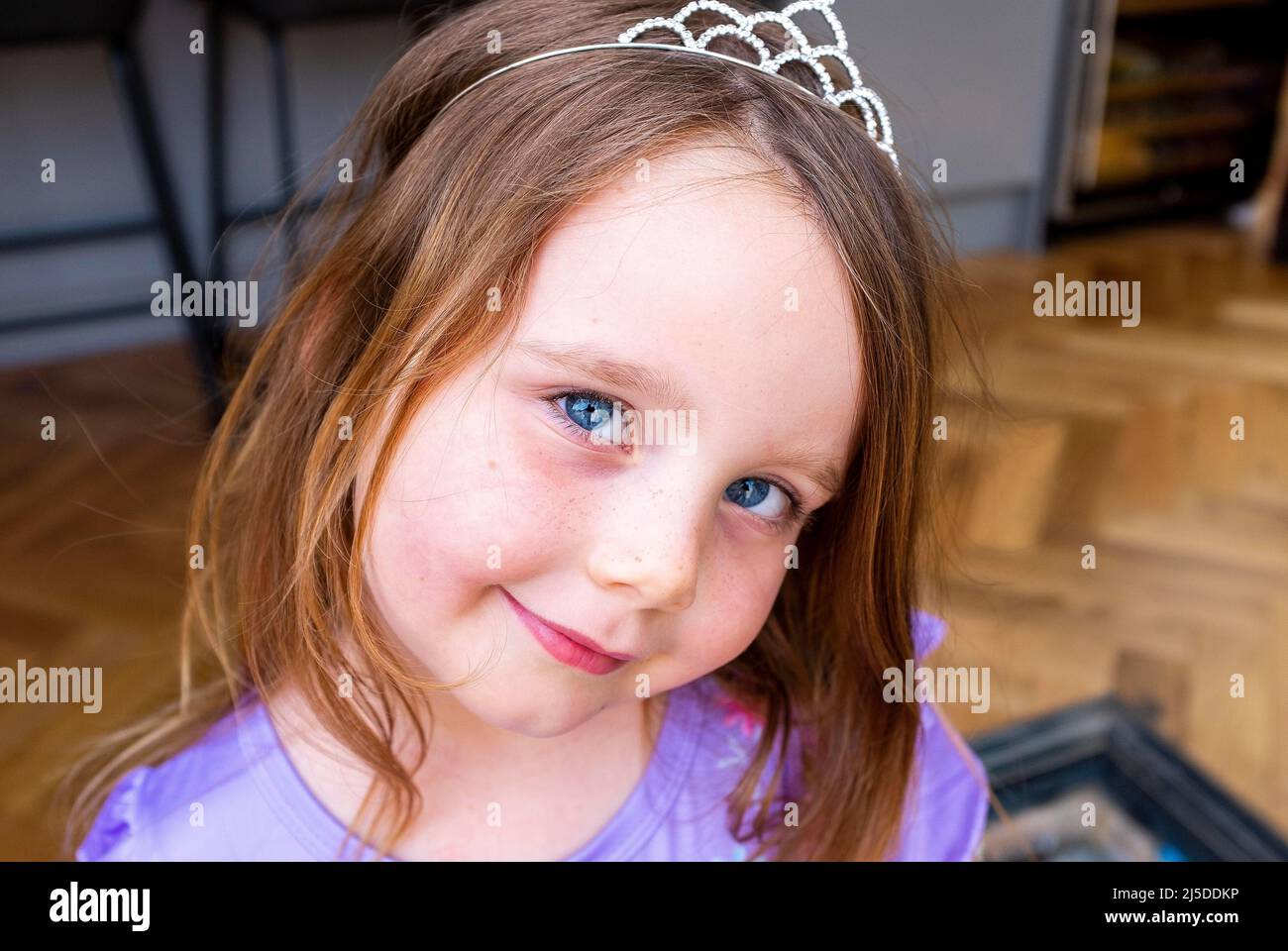 Pretty young five year old girl with blue eyes wearing a toy tiara Stock Photo
