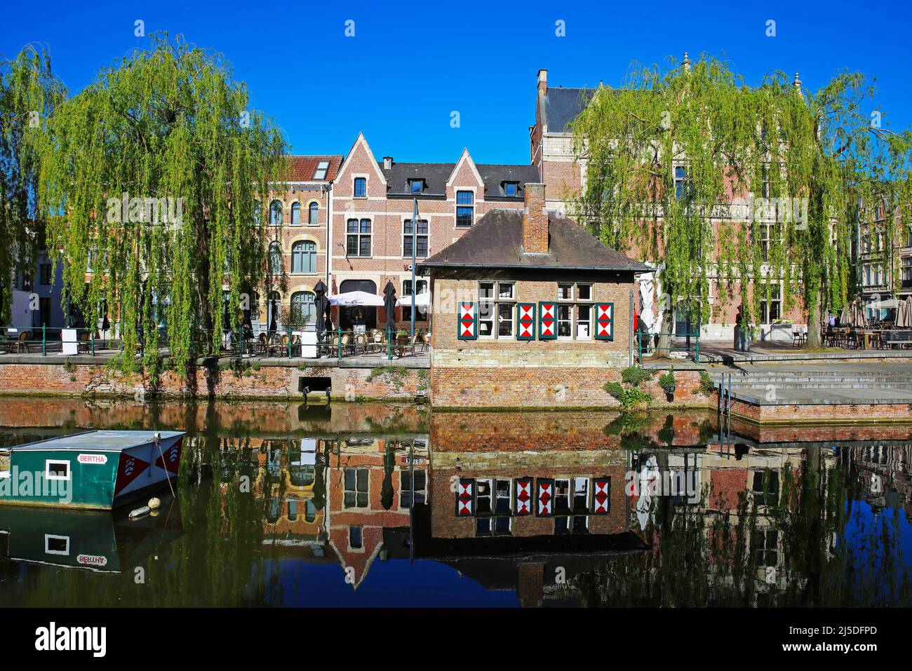 Lier, Belgium - April 9. 2022: View over town moat on old medieval buildings, ancient eel fishing boat, quay with waterfront restaurant, green trees, Stock Photo