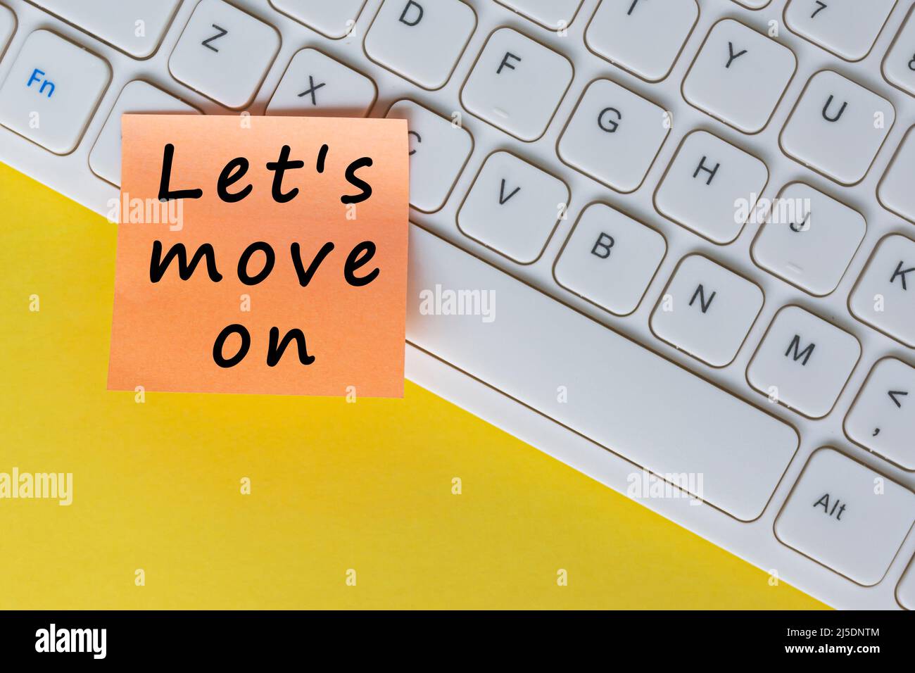 Let's move on text on orange sticky note on top of white keyboard. Stock Photo
